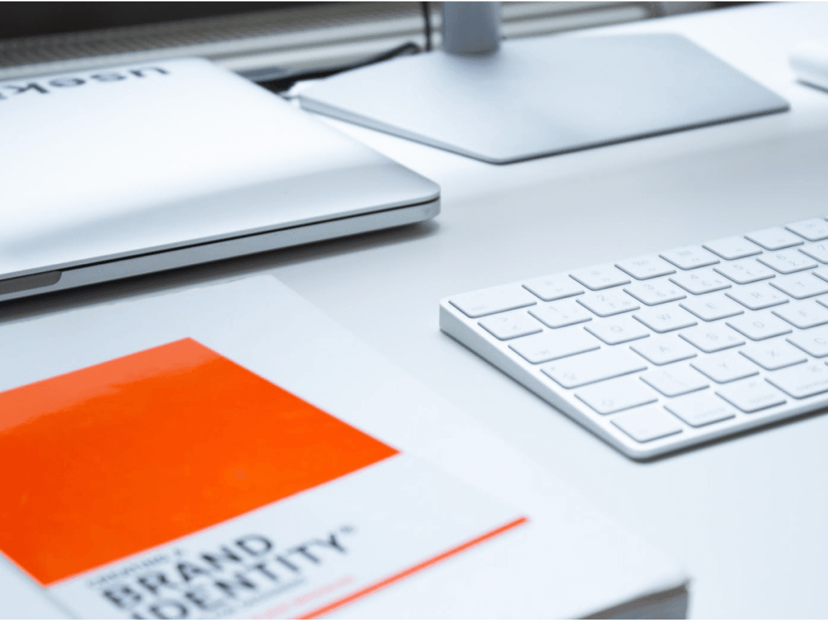 Desk with a keyboard and Brand Identity book