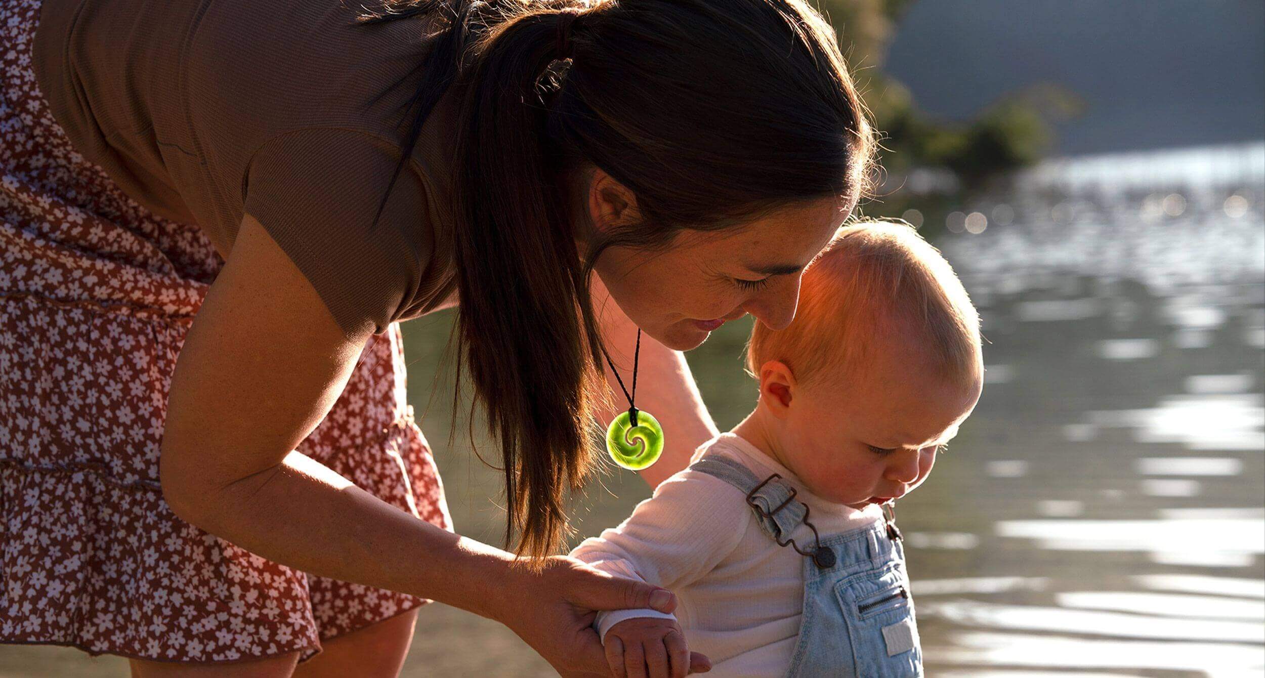 Image of mother with baby, wearing koru